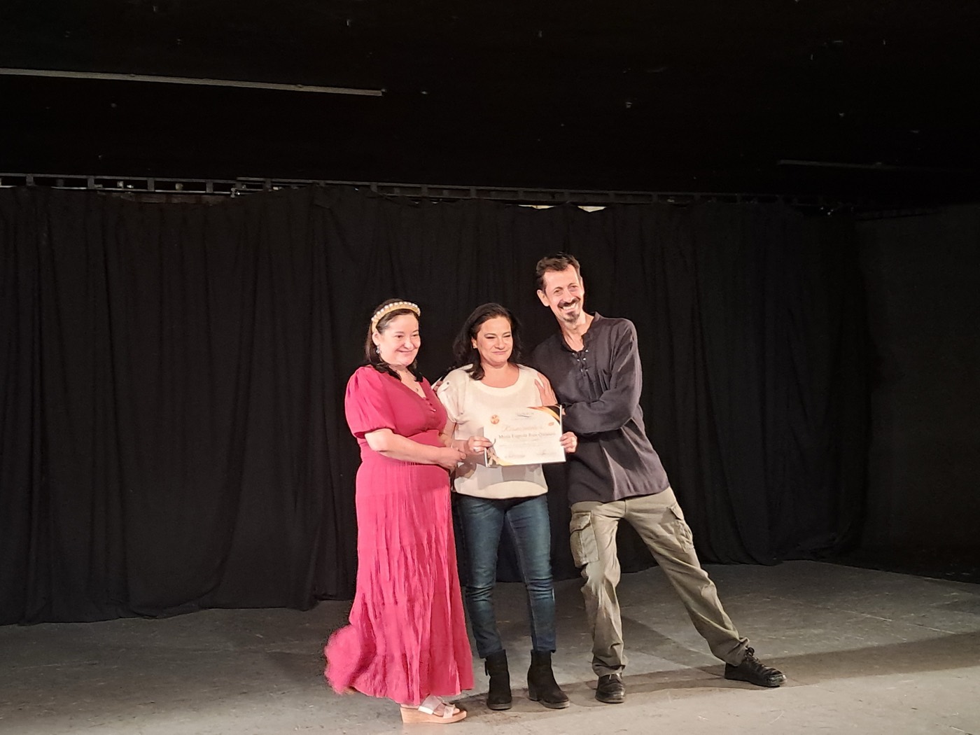 Julio Patricio entrega un reconocimiento a una participante del taller, sobre el escenario.